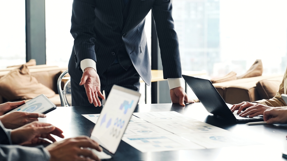 メンバーへ指示を出すスーツ姿の経営者